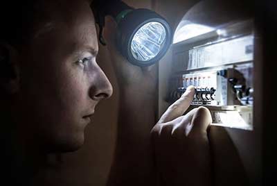 Person working on circuit breaker in the dark 